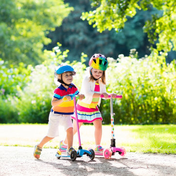 Kids riding scooter in summer park.