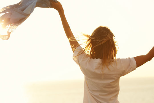 A girl waving its shirt with sunset horizon background