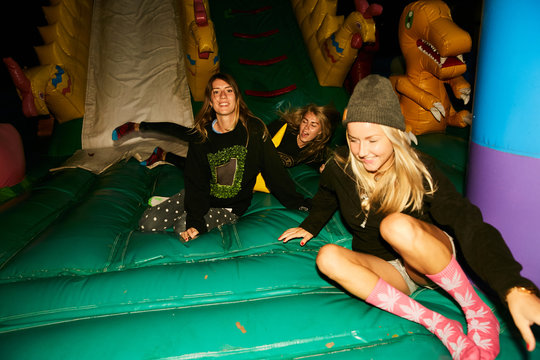 Girls fooling around in an inflatable trampoline like children