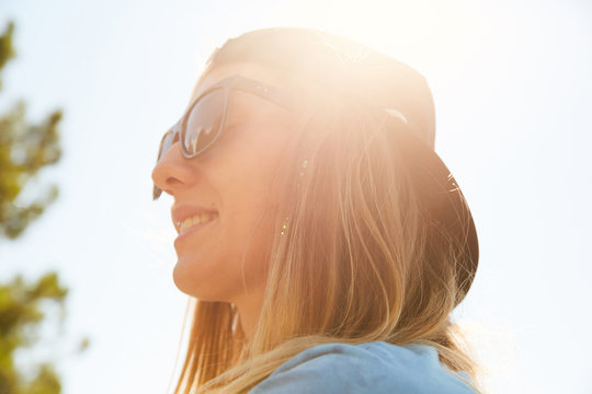 Portrait of a girl in the sun smiling and wearing sunglasses