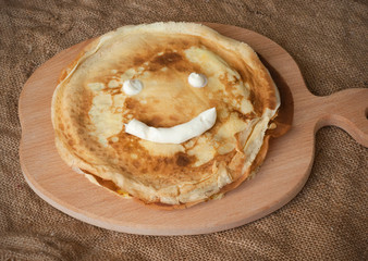 Fried smiling pancakes with sour cream on wooden table