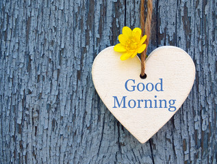 Good Morning.Decorative white wooden heart with primrose flower and  text "good morning" on blue old wooden background.Selective focus.