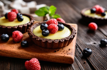 Cocoa tartlets filled with vanilla pudding and topped with blueberry and raspberry © noirchocolate