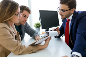 Business man explaining terms of contract to his clients in the office.