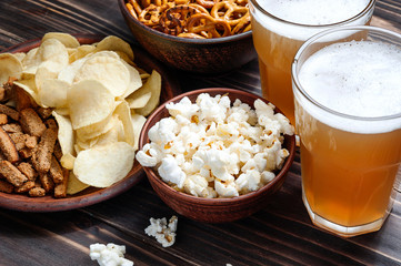 Beer snacks on wooden table - nuts, chips and popcorn in bowls ready for eating.