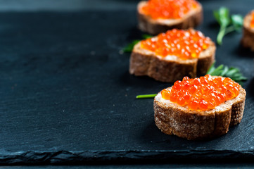 Red caviar on slate background.