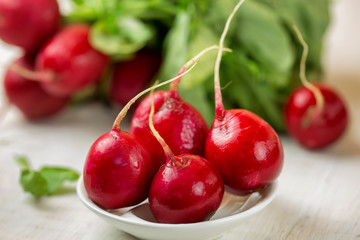 Red radishes in bowl on wooden table. Vegetable of cabbage family. 