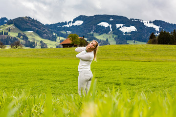 Girl on a meadow in front of the Grueyeres Village in Switzerland
