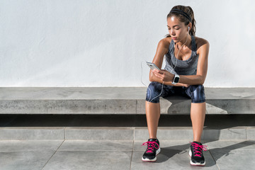 Fitness runner on mobile smart phone app tracking progress listening to music with earphones for...