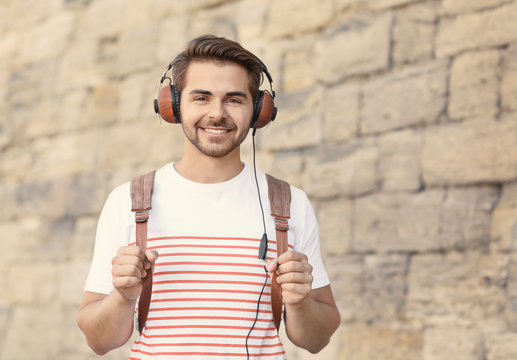 Handsome man with headphones listening music on brick wall background