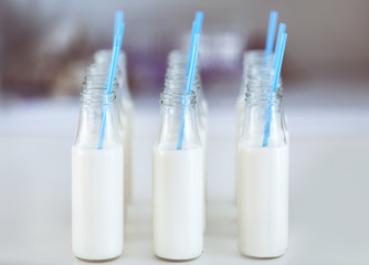 Bottles with milk and straws on table