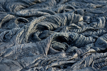 Smooth, undulating surface of frozen pahoehoe lava. Frozen lava wrinkled in tapestry-like folds and...