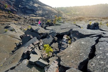 Young female tourist exploring surface of the Kilauea Iki volcano crater with crumbling lava rock in Volcanoes National Park in Big Island of Hawaii © MNStudio