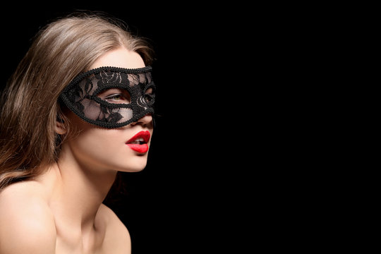 Sexy beautiful woman with carnival mask on black background
