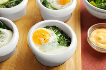 Bowls with tasty eggs and spinach, closeup