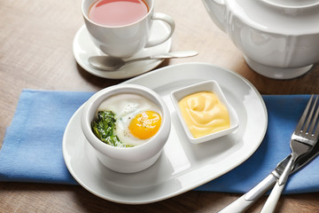 Fototapeta na wymiar Plate with tasty egg and spinach on wooden table