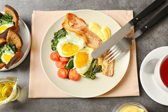 Plate with tasty eggs, spinach and bacon on table