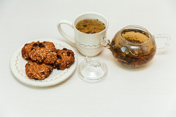 oat cookies,cup of green tea,teapot.white wooden table