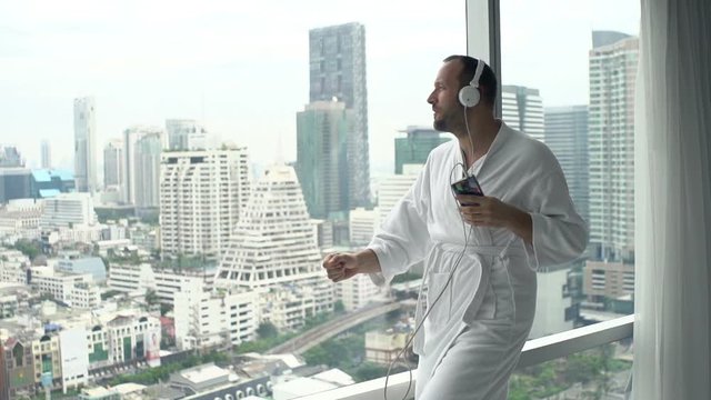 Man dancing, singing while listening to music on cellphone by window, super slow motion 120fps
