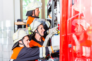 Feuerwehrfrauen schließen Schlauch an Löschfahrzeug an