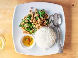 Pad Kaprao Thai traditional dish, fried meat with a basil sauce on a plate, top view