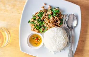Pad Kaprao Thai traditional meal, fried meat with a basil sauce on a plate, top view