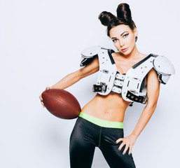 Smiling incredibly beautiful, athletic brunette girl in a shoulderpads and an American football helmet demonstrating stunning amazing abs. White background. NFL. Super bowl. Footy. Sexy. Having fun.