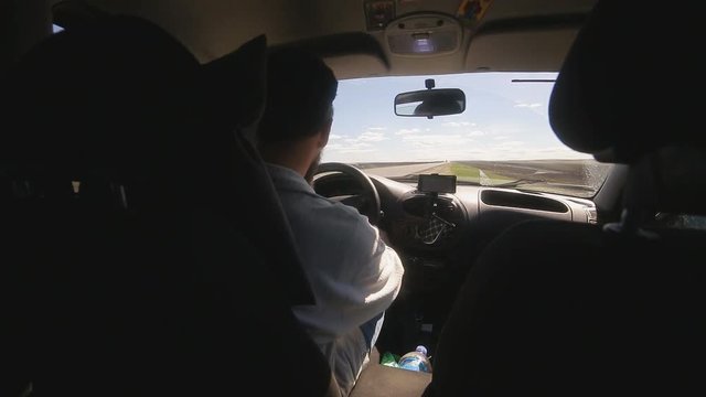 A man gets into the car and turns on the navigator on the smartphone