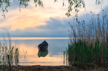 Old rowboat on the lake at sunset
