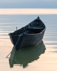 Old rowboat on the lake at sunset