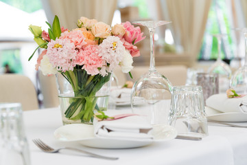 Flower table decorations for holidays and wedding dinner. Table set for holiday, event, party or wedding reception in outdoor restaurant.