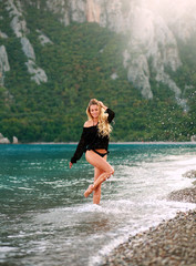 Dreamy sensual woman enjoys nature of sea in water splashes