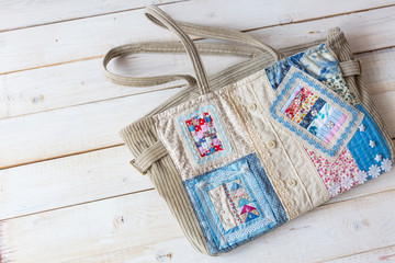handmade, fashion, accessories concept -flatlay of charming women's bag made of velveteen and front part sewing in technique patchwork with colorful ornate snippets. it has two straps, lace and button