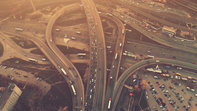 Aerial high drone flight over evening road traffic in Kiev, Ukraine. Highway and overpass with cars and trucks, interchange, two-level road junction in the big city. Top view. Vintage filter toning