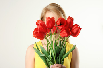 Beautiful young woman with bouquet of tulips on white background