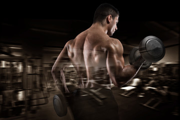 Fototapeta na wymiar Athletic man training biceps on gym background