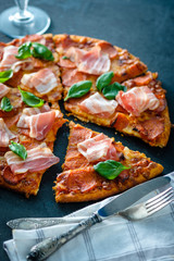 Homemade Pepperoni Pizza with fresh bacon over black background