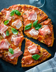 Homemade Pepperoni Pizza with fresh bacon over black background