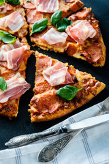 Homemade Pepperoni Pizza with fresh bacon over black background