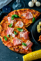 Homemade Pepperoni Pizza with fresh bacon over black background