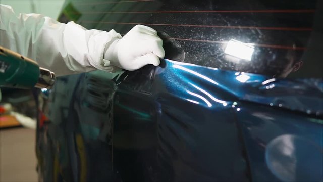 Employee garage heats hairdryer continuous surface vinyl film. Heating is necessary in order to cover well fixed.