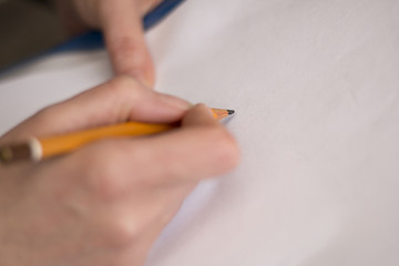 Woman's hand holding wooden pencil over empty paper, ready to write or draw