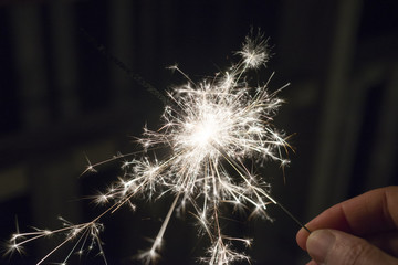 Festive sparkler held in hand, brightly burning at night during celebration event