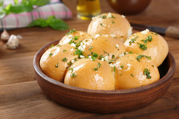 Wooden bowl with tasty garlic bread rolls on kitchen table