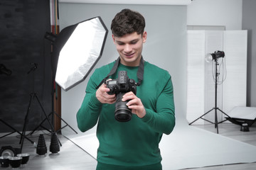 Young professional photographer with camera in studio