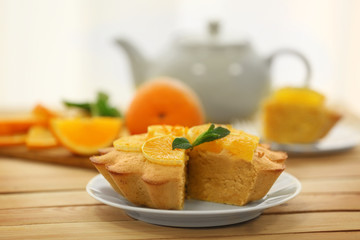 Plate with delicious citrus cake on wooden table