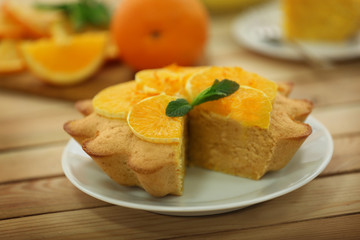 Plate with delicious citrus cake on wooden table