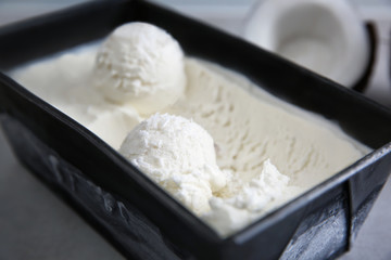 Black container with fresh coconut ice cream, closeup