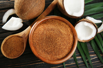 Bowl and spoon of brown sugar with coconut on wooden background