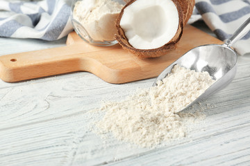 Metal scoop with coconut flour on wooden background